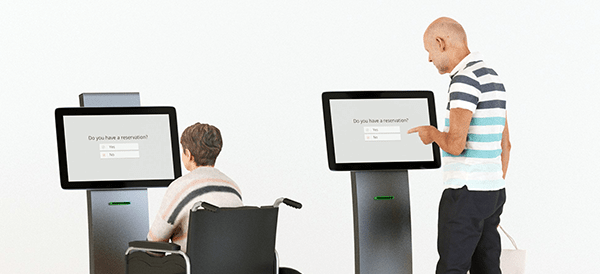 person in wheelchair using kiosk with standing person using kiosk